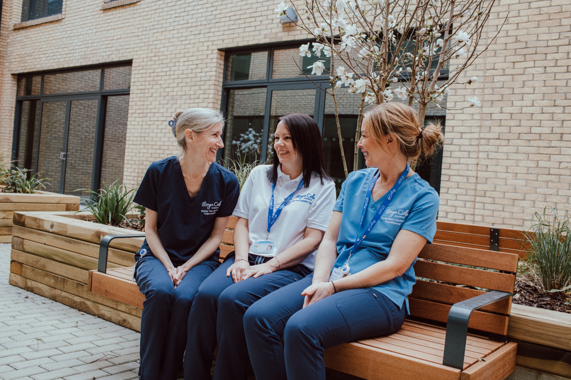 Three Moyacole hospice staff members sitting together on a bench
