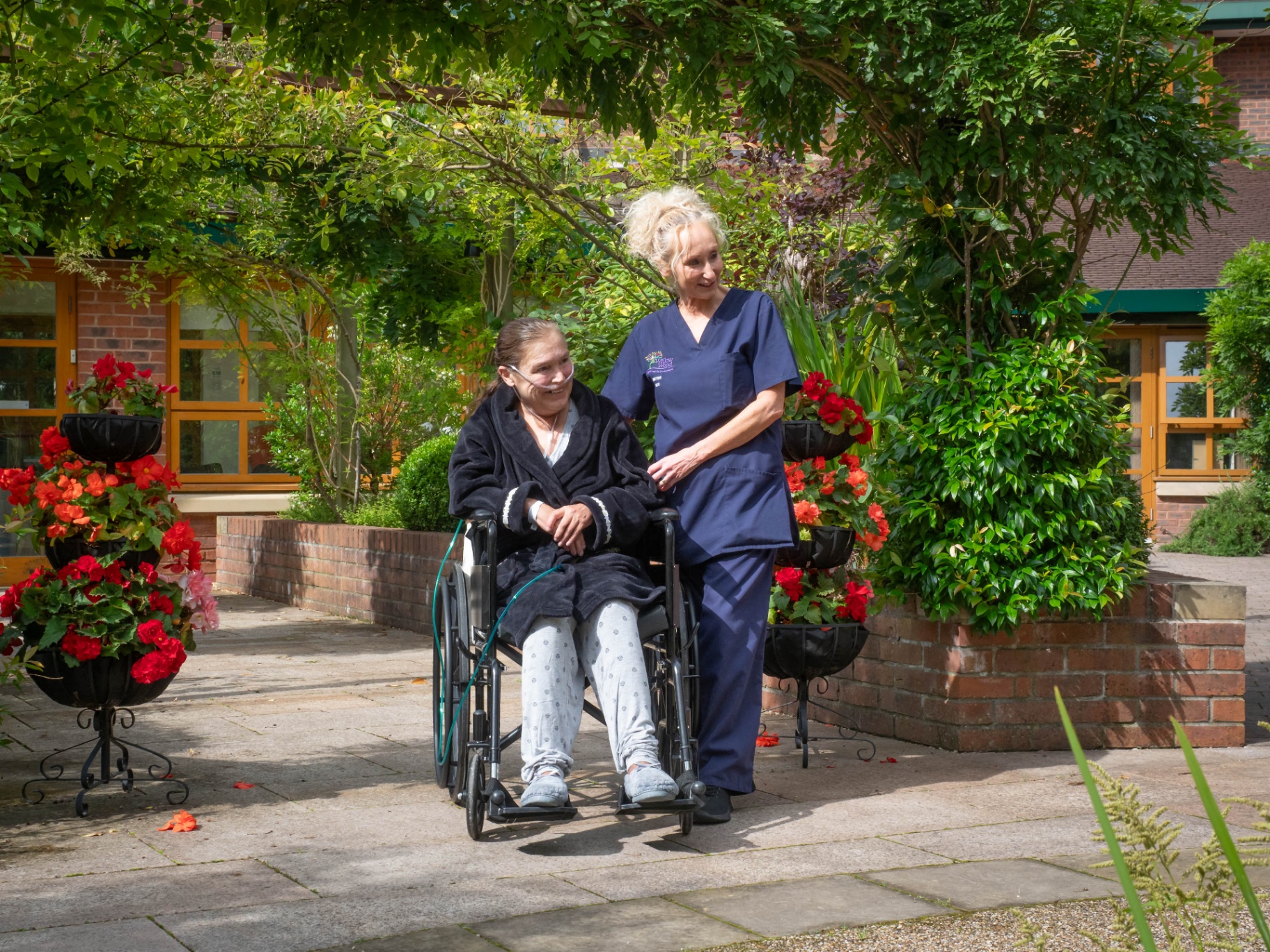 Hospice nurse walking with a patient through a flower-filled garden